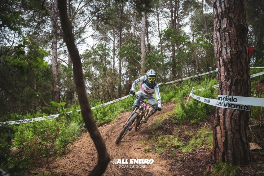 Curva piatta nel fango con bici inclinata e piede esterno basso per aumentare stabilità