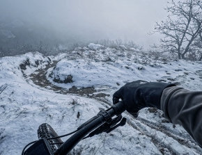 Visuale dal manubrio su sentiero innevato e scivoloso, tra alberi spogli e nebbia